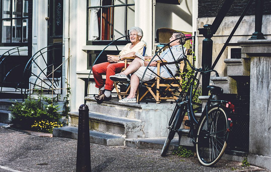 Pareja mayor disfrutando de la tarde y una bicicleta aparcada en la puerta de su casa de Ámsterdam