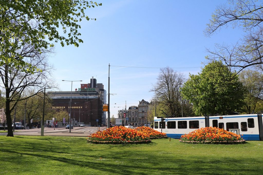 Fachada de la antigua fábrica de Heineken en Ámsterdam con un tranvía pasando delante.