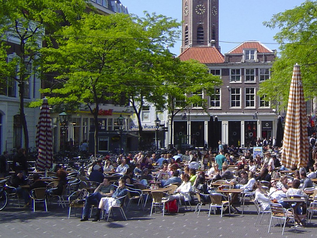 Terrazas al aire libre en Grote Markt, La Haya, con mesas llenas de gente disfrutando del sol en verano