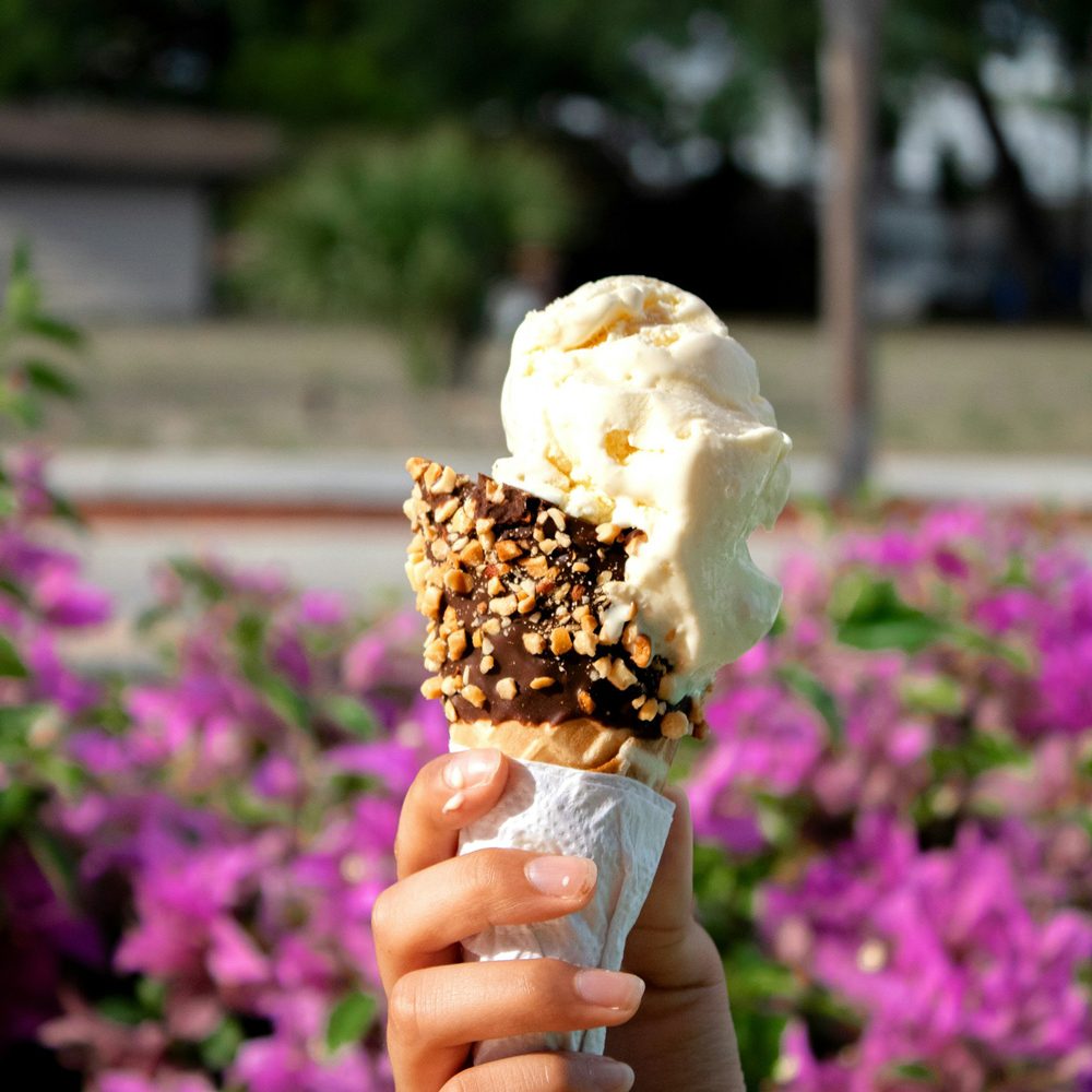 Helado artesanal en primer plano con un parque al fondo, ideal para disfrutar del verano en la ciudad.
