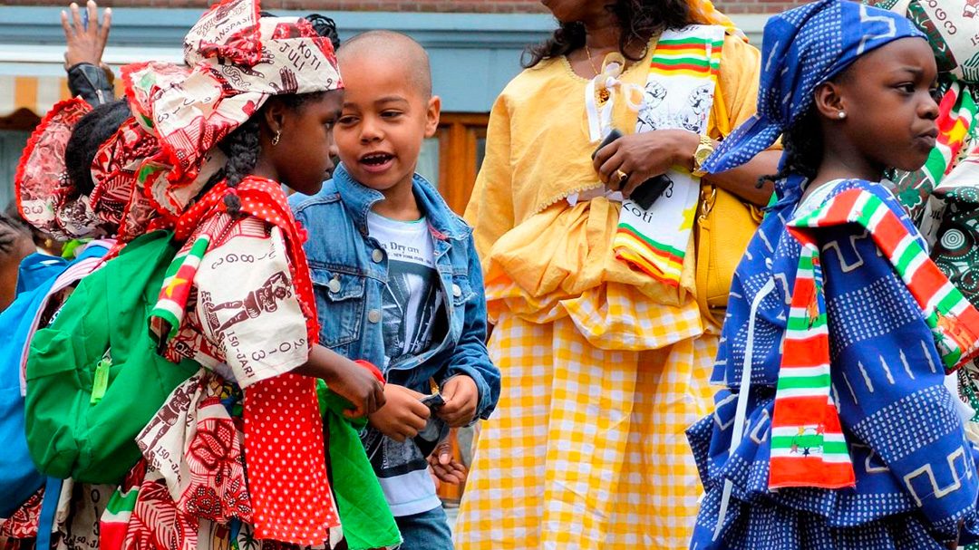 Niños vestidos con ropa típica de Surinam disfrutando la celebración Keti Koti.