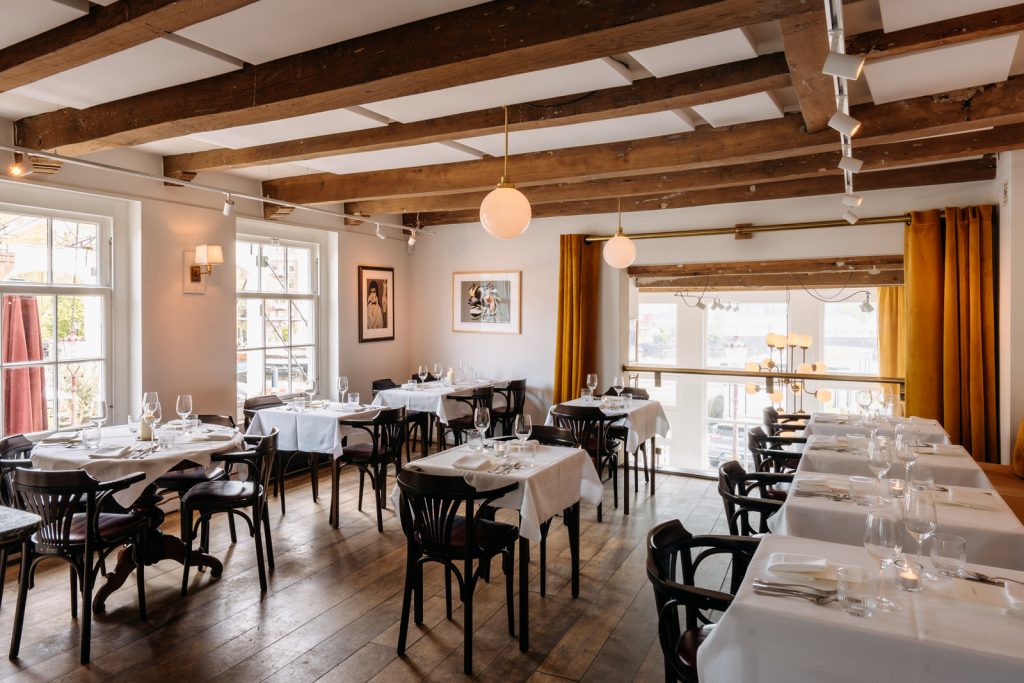 Interior del restaurante Tannay en Ámsterdam con iluminación cálida y ambiente acogedor.