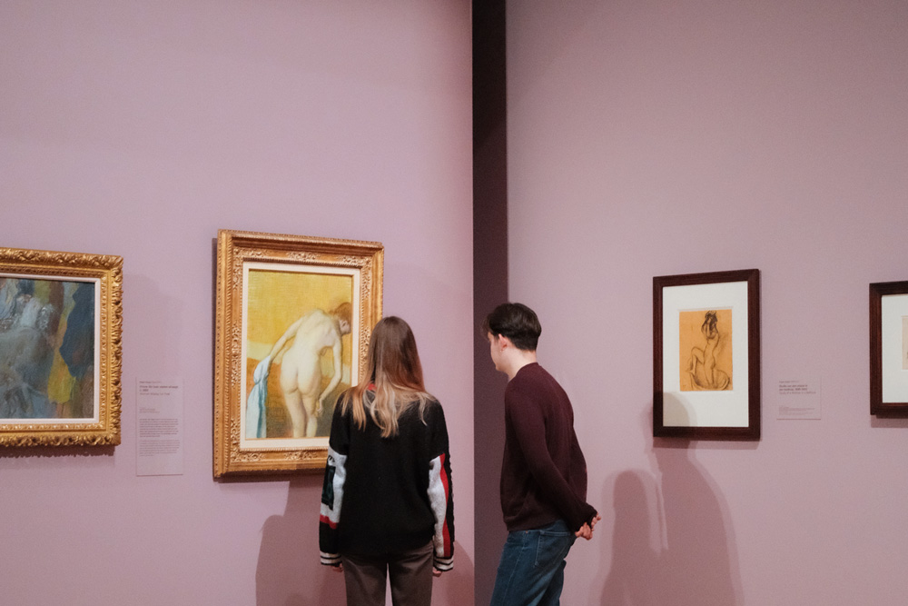 Visitantes en el Museo Van Gogh contemplando varias pinturas del artista en una sala expositiva.