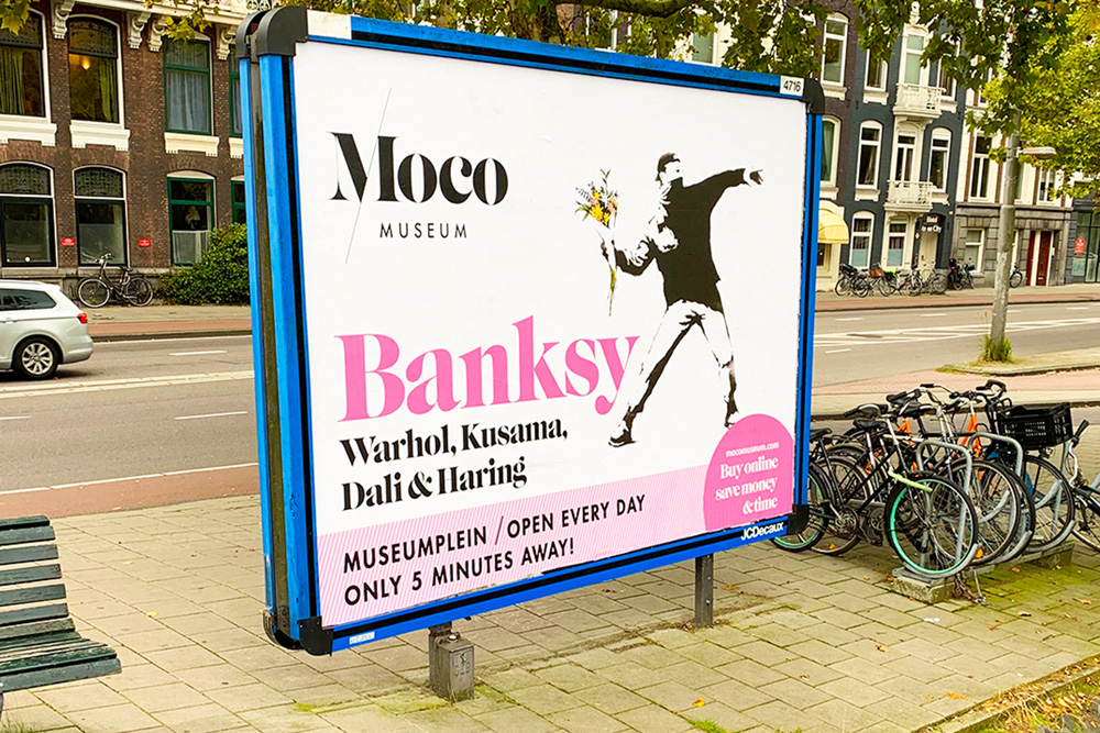 Publicidad callejera en Ámsterdam con la obra “Flower Thrower” de Banksy promocionando el Moco Museum.