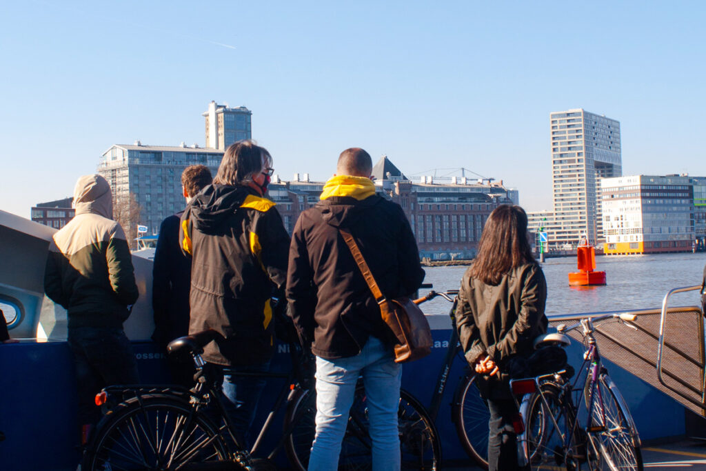 Viajeros en el ferry gratuito de Ámsterdam cruzando el IJ hacia el norte de la ciudad en un día soleado de invierno.