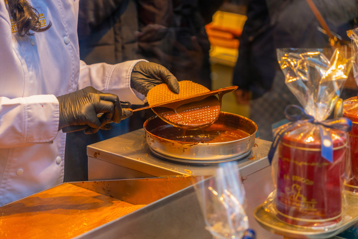 Mujer untando un stroopwafel en chocolate caliente dentro de una tienda de Ámsterdam, en el contexto de San Valentín.