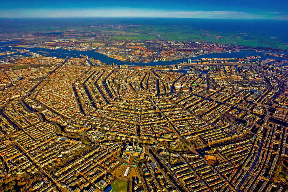 Vista aérea de Ámsterdam mostrando el anillo de canales Grachtengordel, ejemplo de planificación urbana del Siglo de Oro neerlandés.