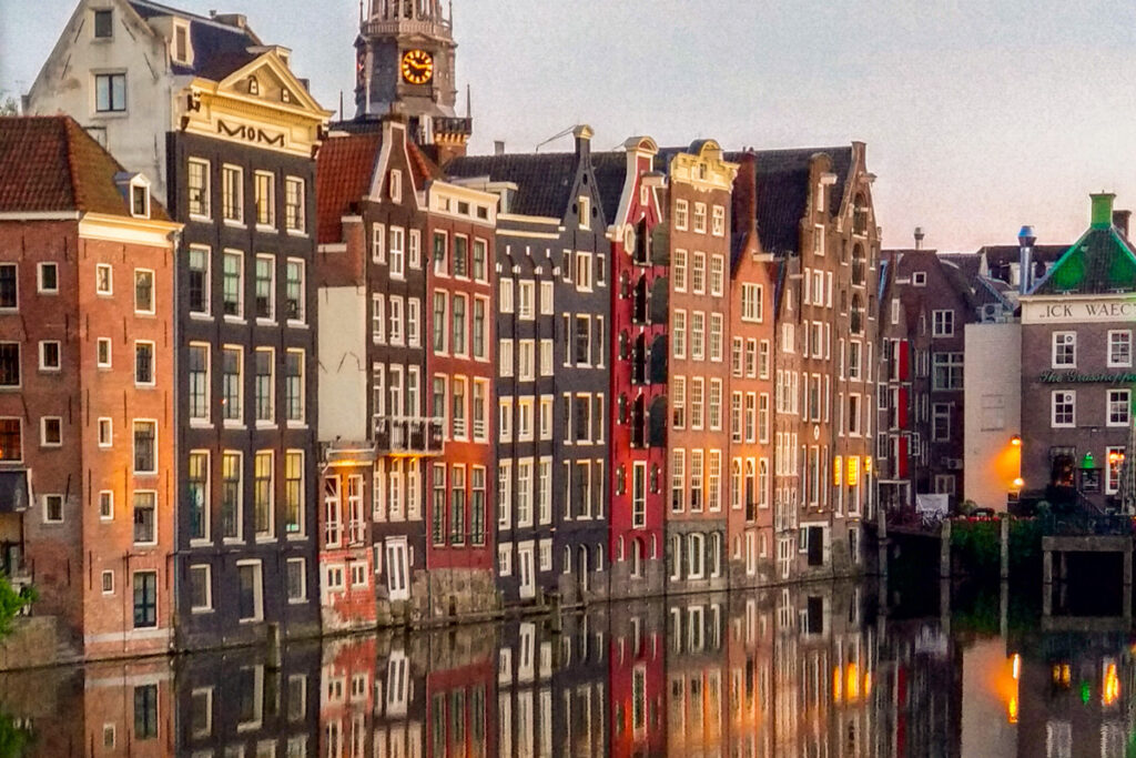 Canal de Ámsterdam al anochecer, con casas históricas del siglo XVII reflejadas en el agua, arquitectura típica del Siglo de Oro neerlandés.
