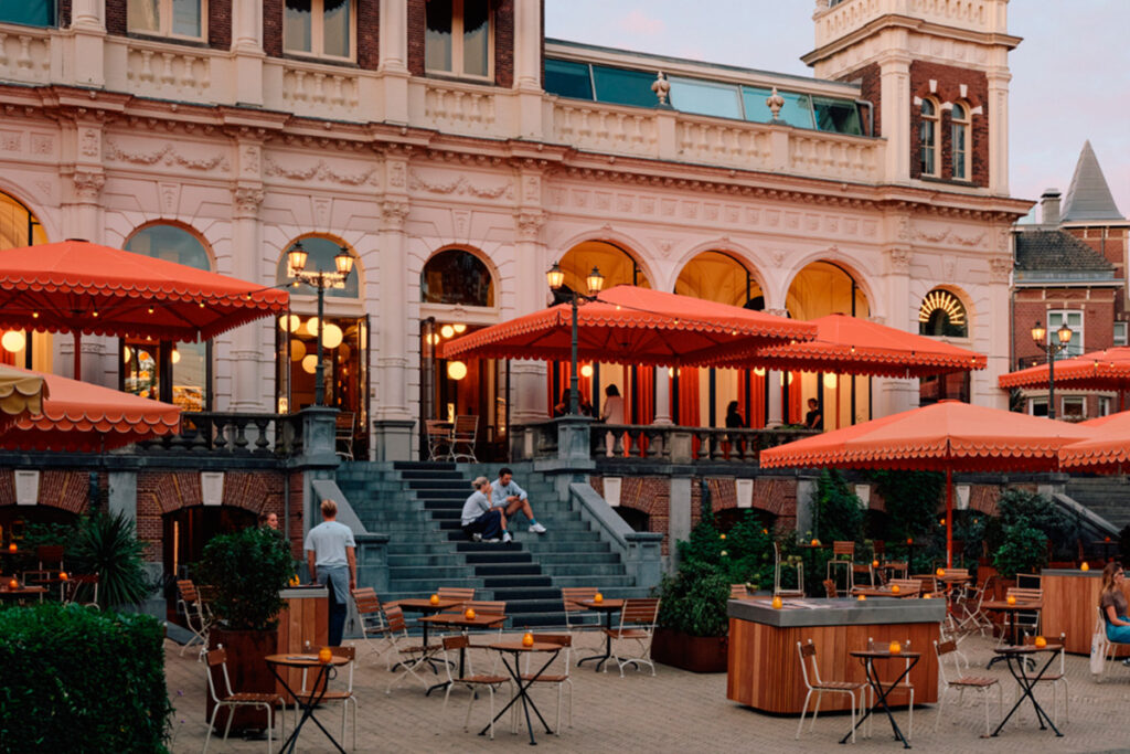 Terraza del restaurante Vertigo en Vondelpark, vista desde la entrada antes de las escaleras, con mesas al aire libre en un entorno verde.