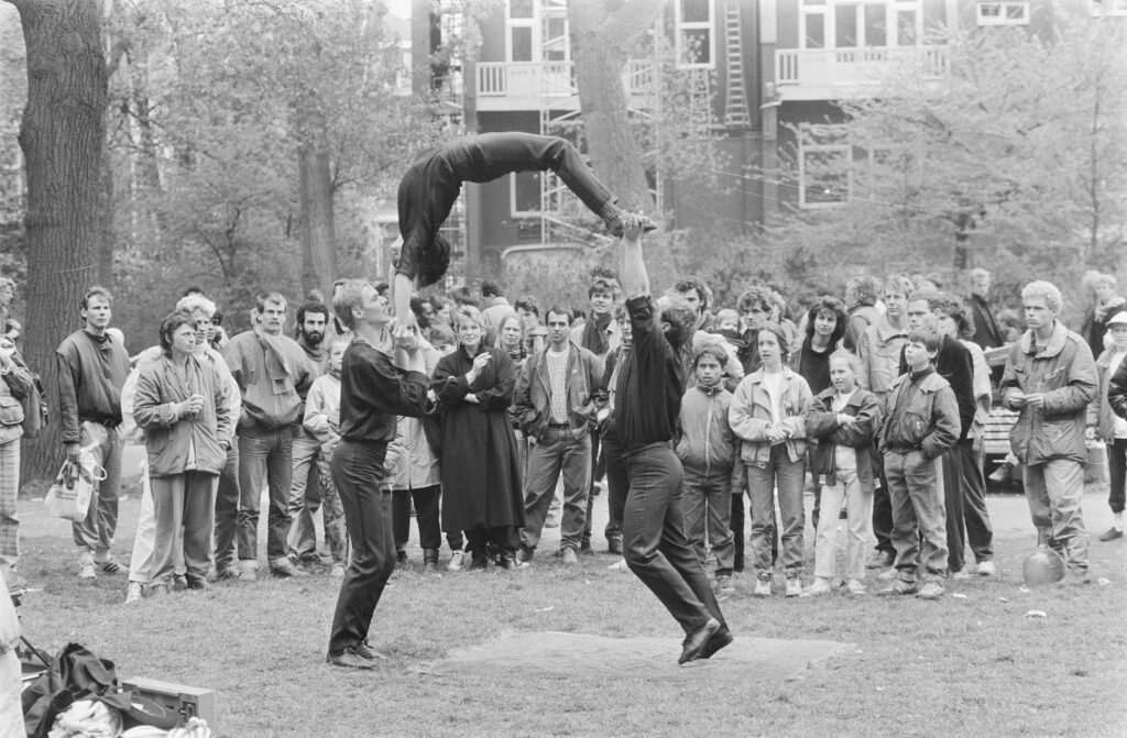 Acróbatas actuando en Vondelpark durante el Día de la Liberación en Ámsterdam, con público observando el espectáculo.