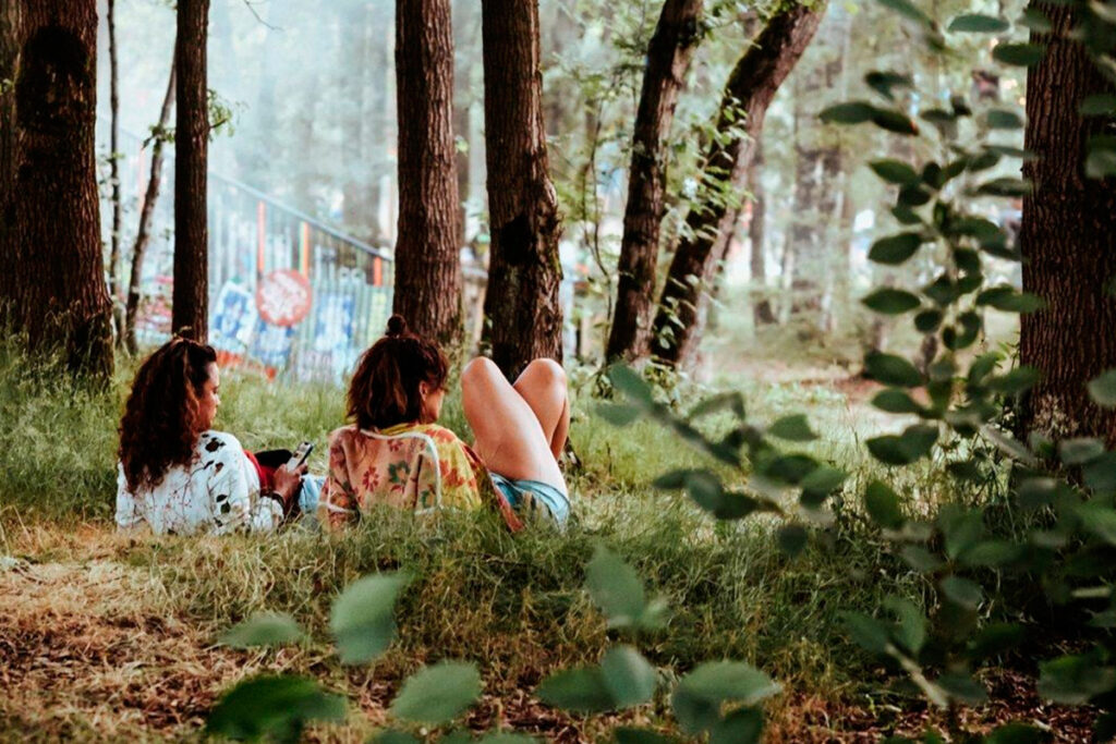 Dos chicas tumbadas en el bosque durante el Best Kept Secret Festival, descansando en un entorno natural en verano.