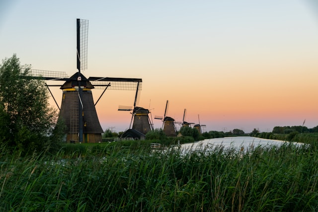 Molino de viento tradicional en Kinderdijk junto a un canal, con paisaje típico neerlandés.