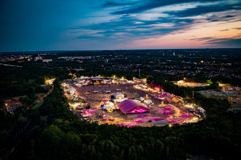 Escenario del Pinkpop Festival de noche con iluminación rosada y público frente al concierto en los Países Bajos.