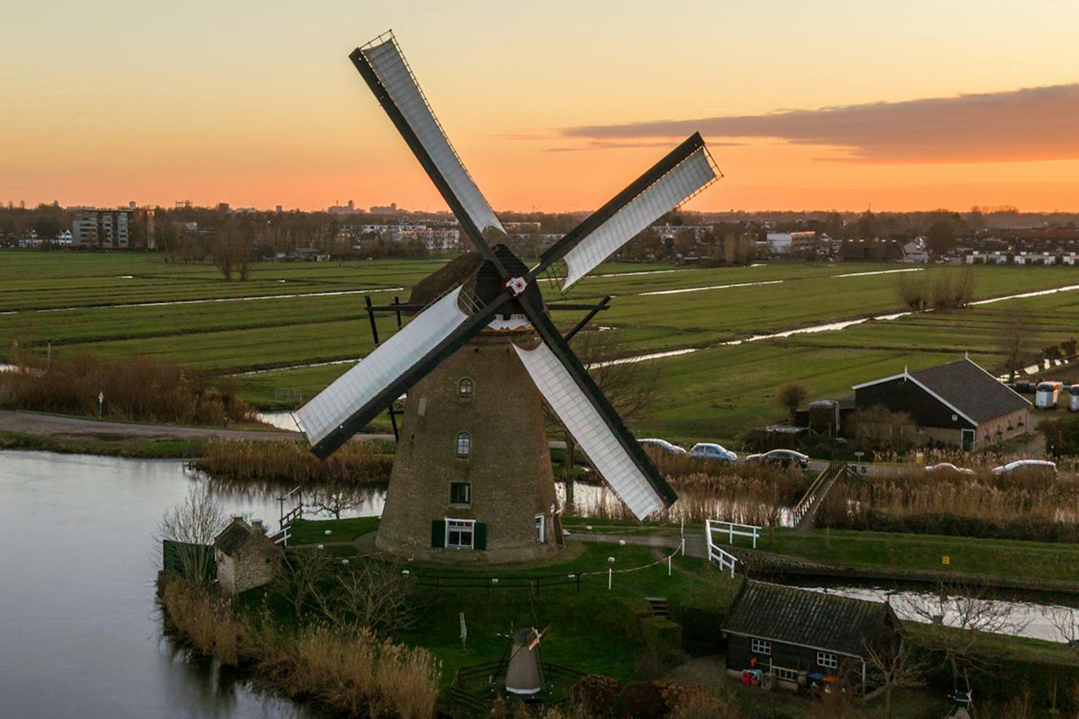 Molino de viento en Schermer con paisaje de pólder, canales y cielo abierto en los Países Bajos.