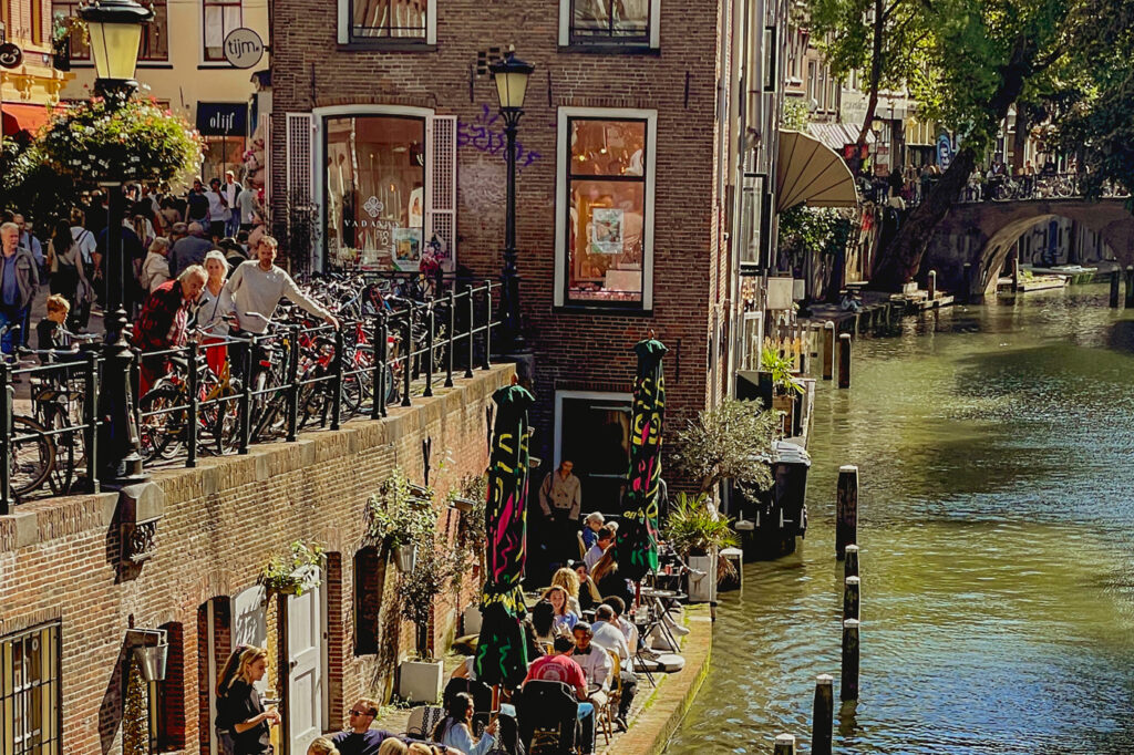 Terrazas junto al canal en Utrecht, con personas disfrutando al sol en un día de verano.