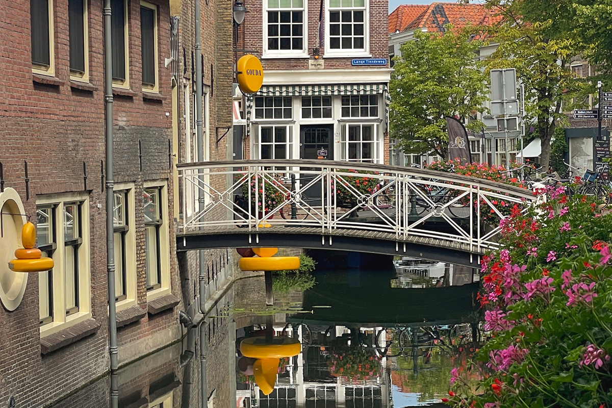 Canal y puente en Gouda con un letrero circular amarillo de la ciudad junto al agua.