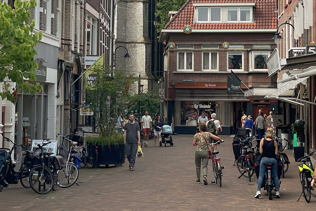 Personas paseando por el centro histórico de Gouda en un día tranquilo entre calles y edificios tradicionales.