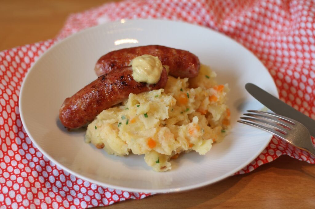 Plato de hutspot holandés con puré de patata, zanahoria y cebolla servido de forma tradicional.