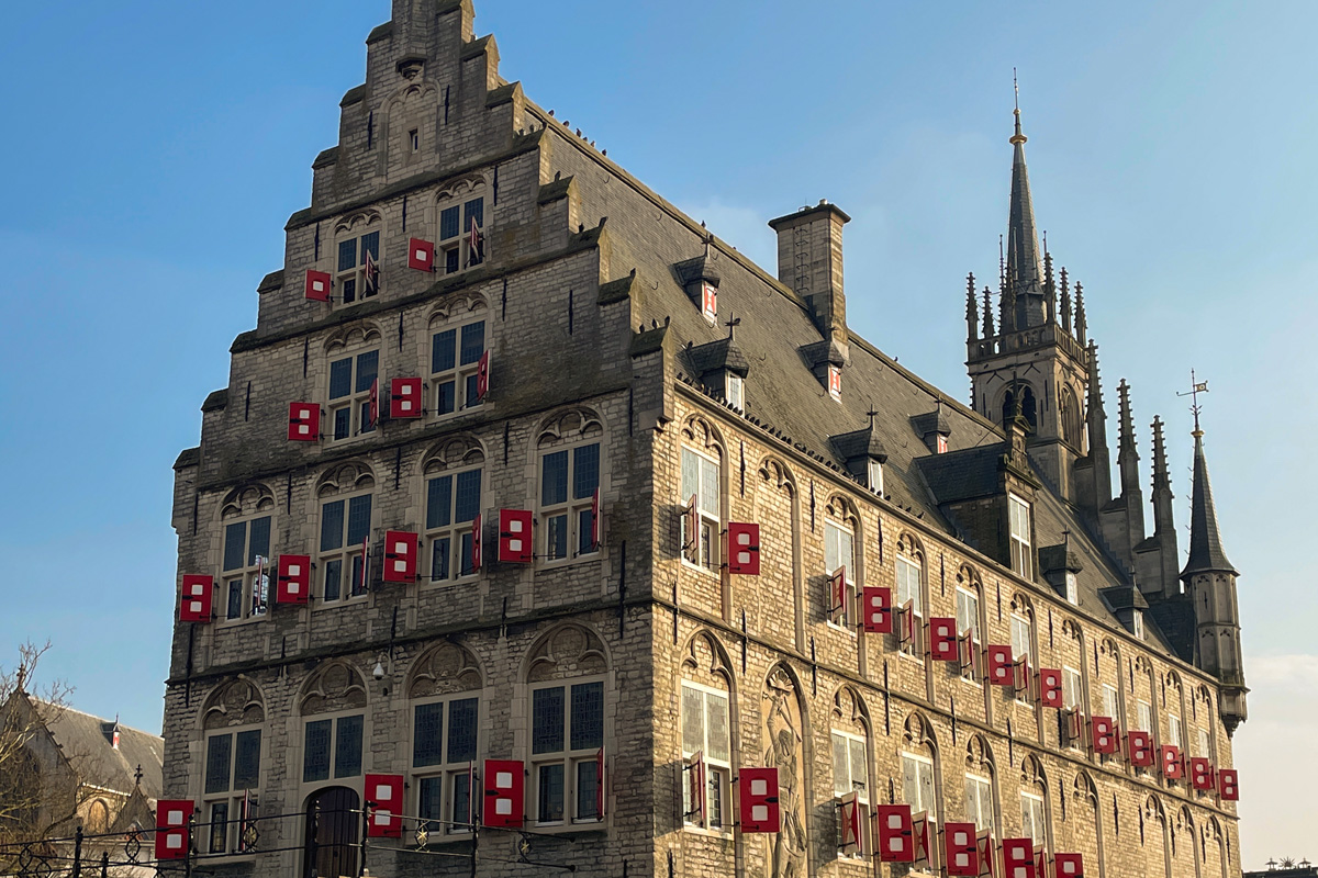 Ayuntamiento histórico de Gouda con fachada gótica y cielo azul en la plaza principal de la ciudad.