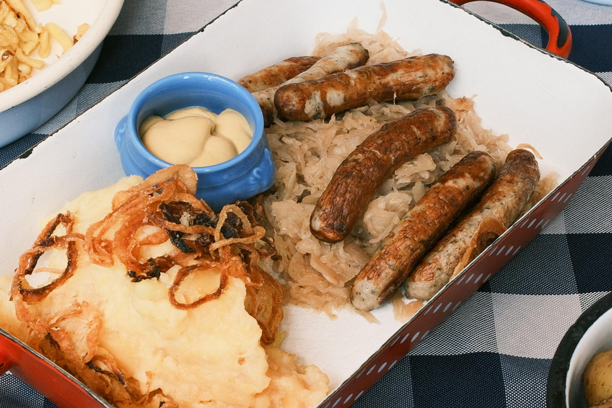 Plato tradicional de stamppot neerlandés con puré de patata, col rizada y salchicha ahumada.