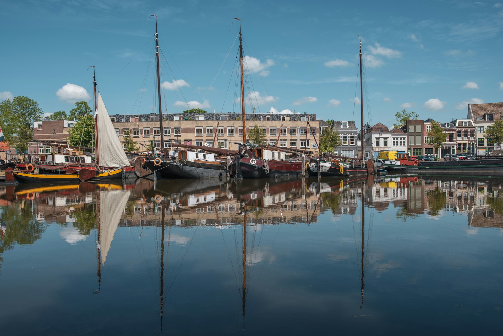 Barcos tradicionales anclados en un canal de Gouda con edificios históricos de la ciudad al fondo.