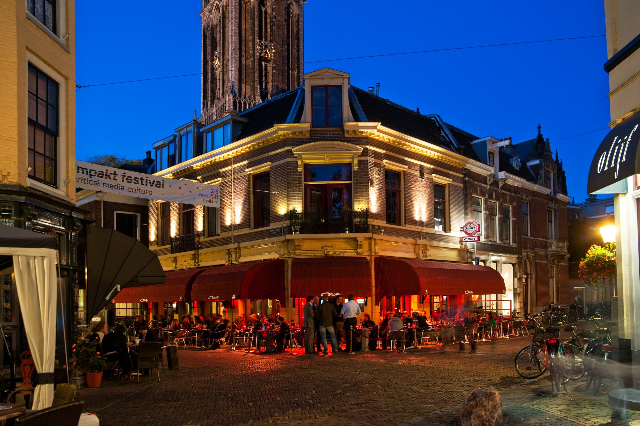 Terraza del Café Orloff en Utrecht al anochecer, con clientes disfrutando junto al canal Oudegracht.