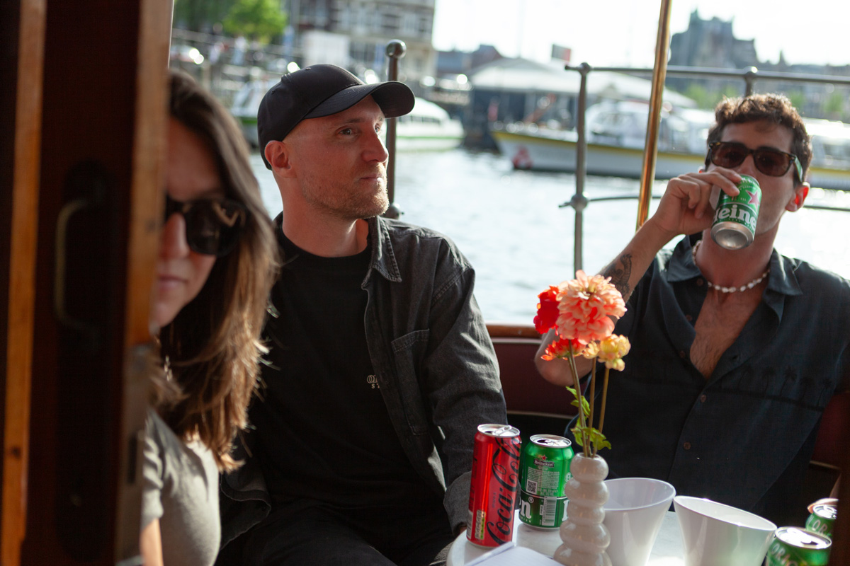Jóvenes disfrutando de una cerveza Heineken a bordo de un barco de Camaleón Tours mientras navegan por los canales de Ámsterdam.