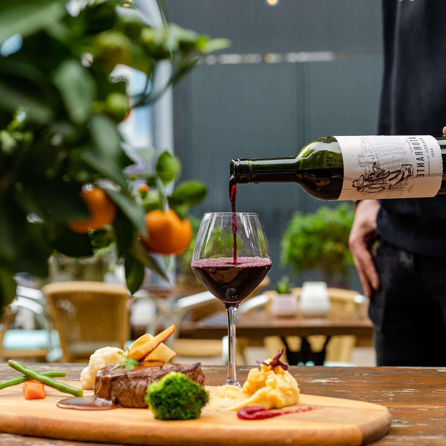 Mesa preparada en la terraza de Restaurant LOOF mientras se sirve una copa de vino tinto.