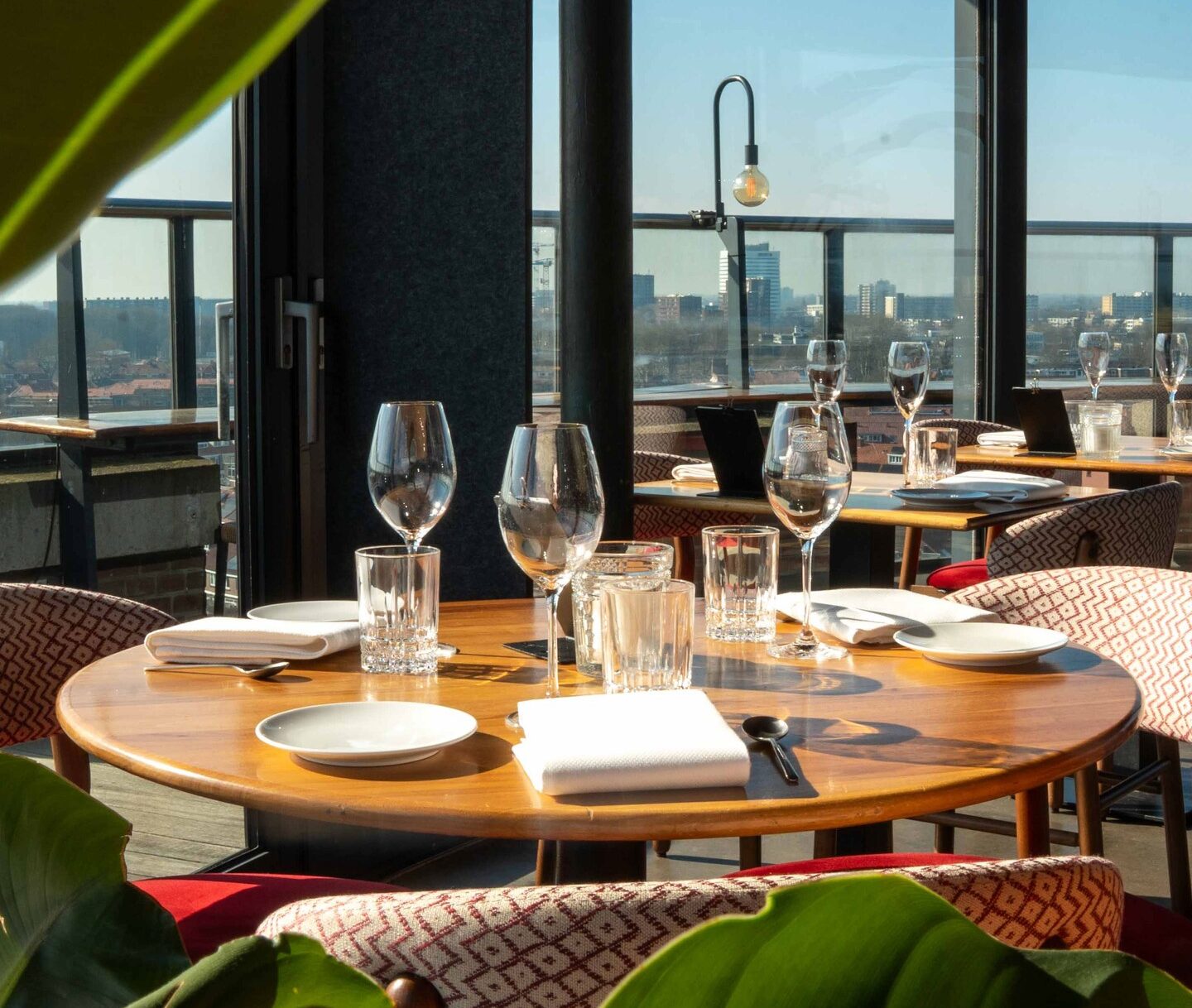 Mesa preparada para un almuerzo en la terraza de WT Urban Kitchen con vistas panorámicas a la ciudad de Utrecht en un día soleado.