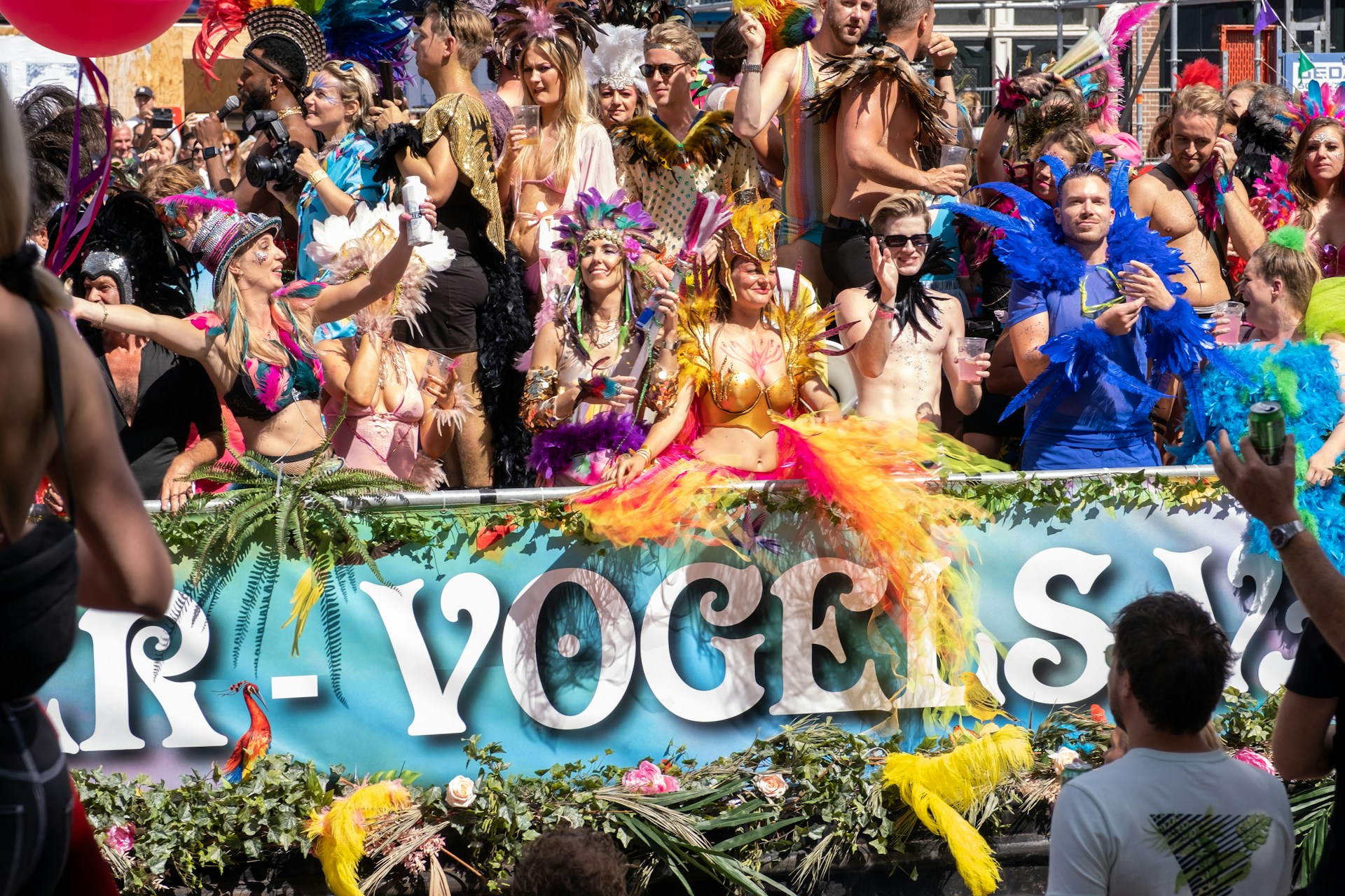 Personas disfrutando de un evento musical al aire libre durante el Orgullo de Ámsterdam, con atuendos coloridos y ambiente festivo.