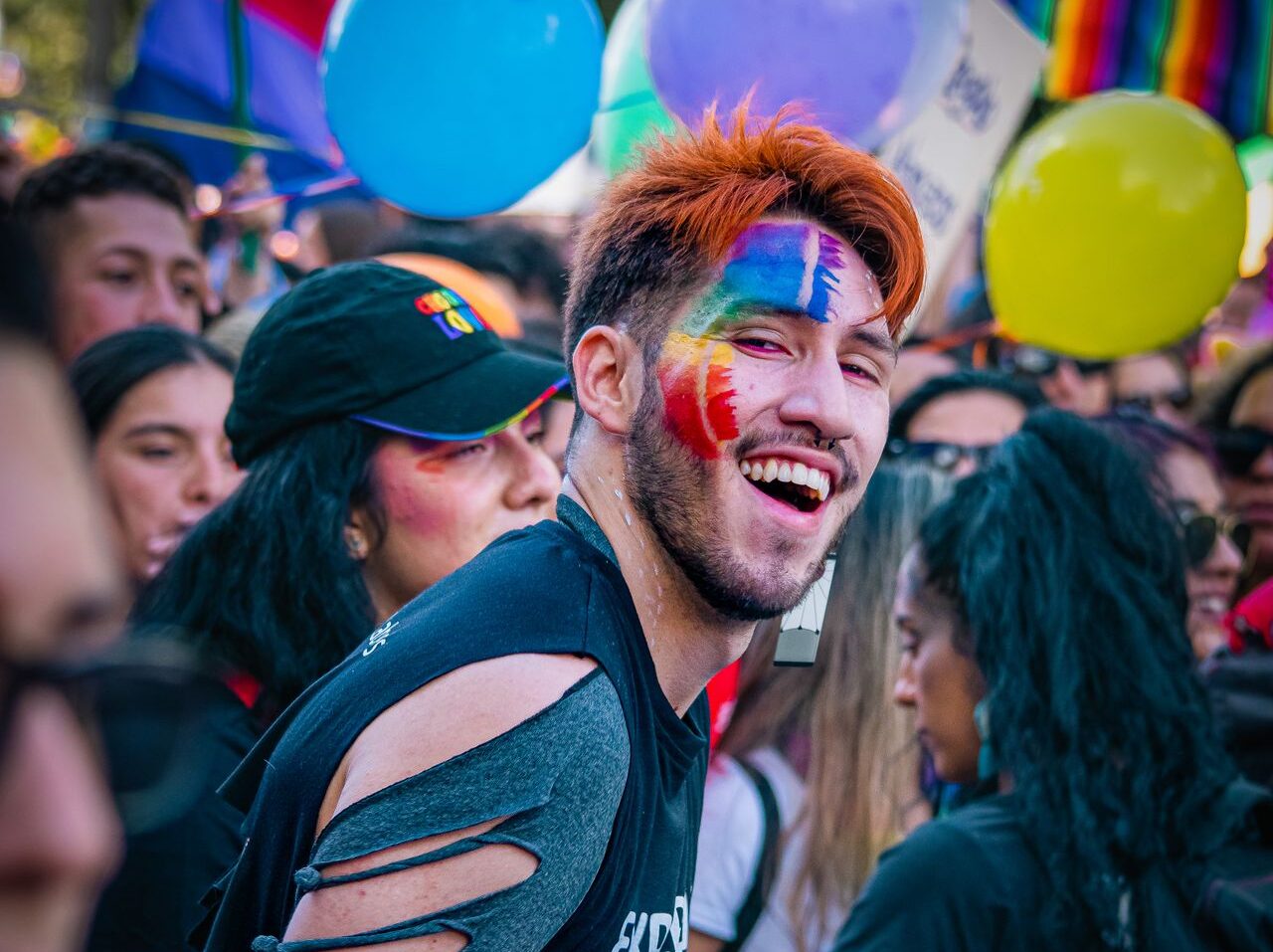 Participante en los eventos del orgullo en Ámsterdam con colores del orgullo en el rostro.