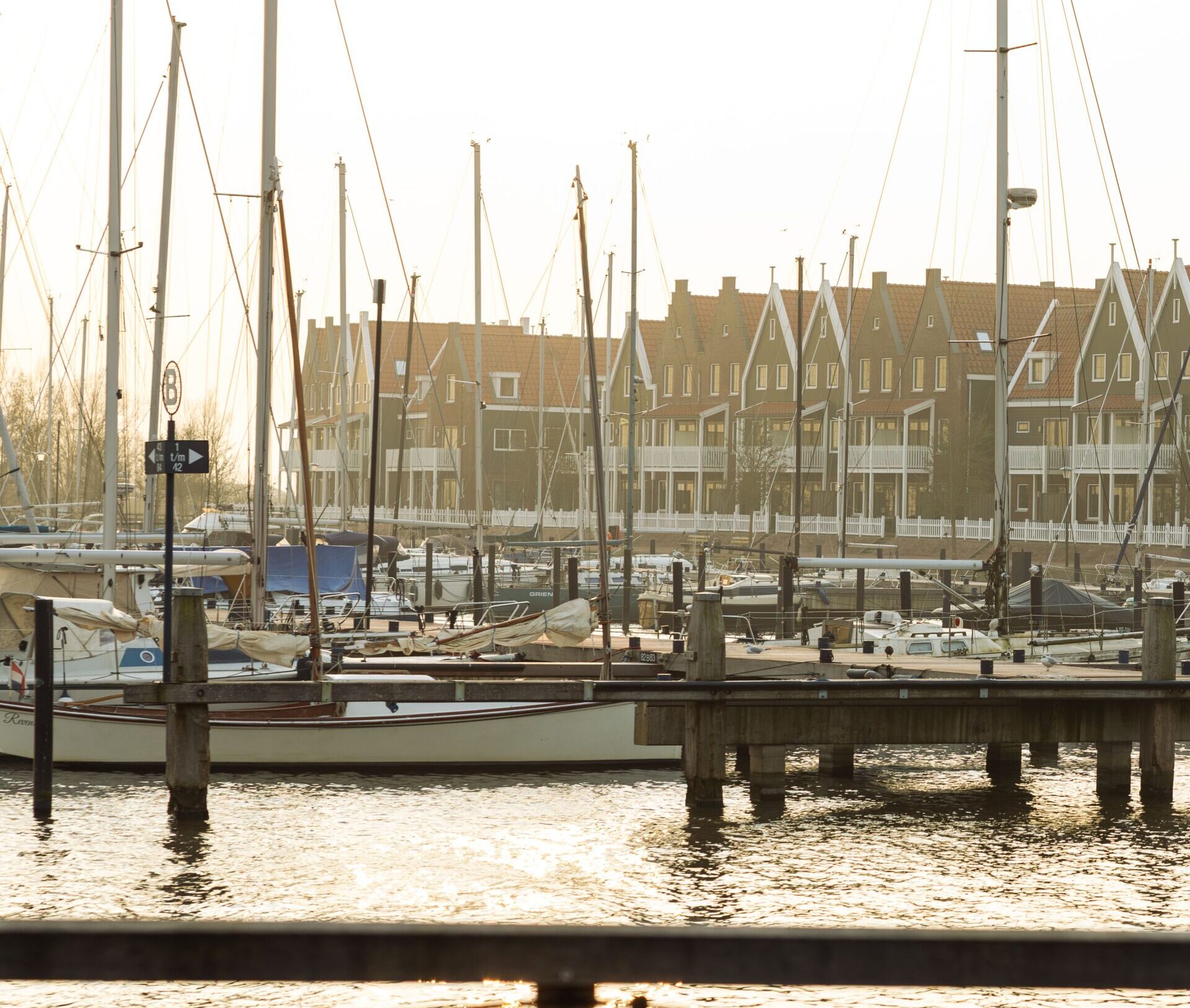 Barcos atracados en el puerto de Volendam durante la tarde, con las casas tradicionales del pueblo al fondo.