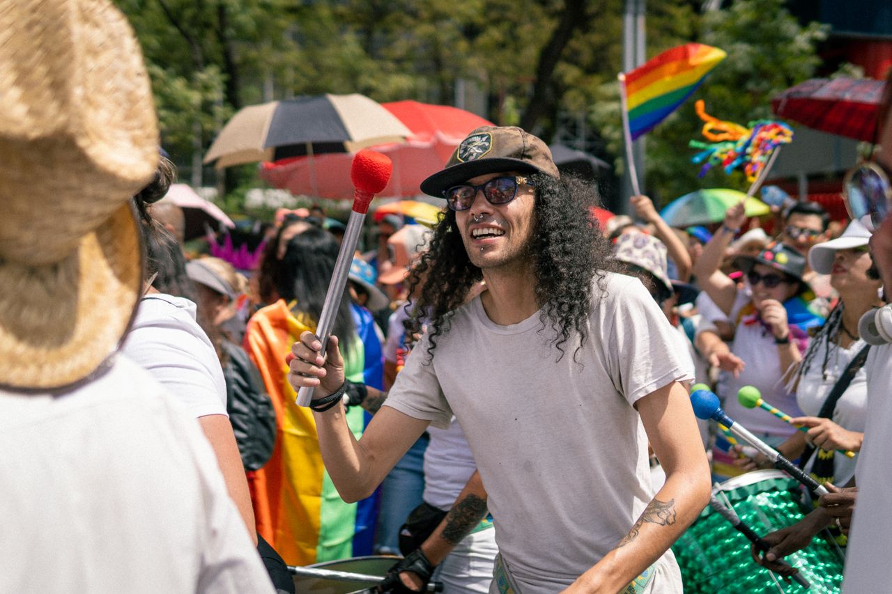 Personas con tambores y banderas participando en la Pride March de Ámsterdam durante el Mes del Orgullo.