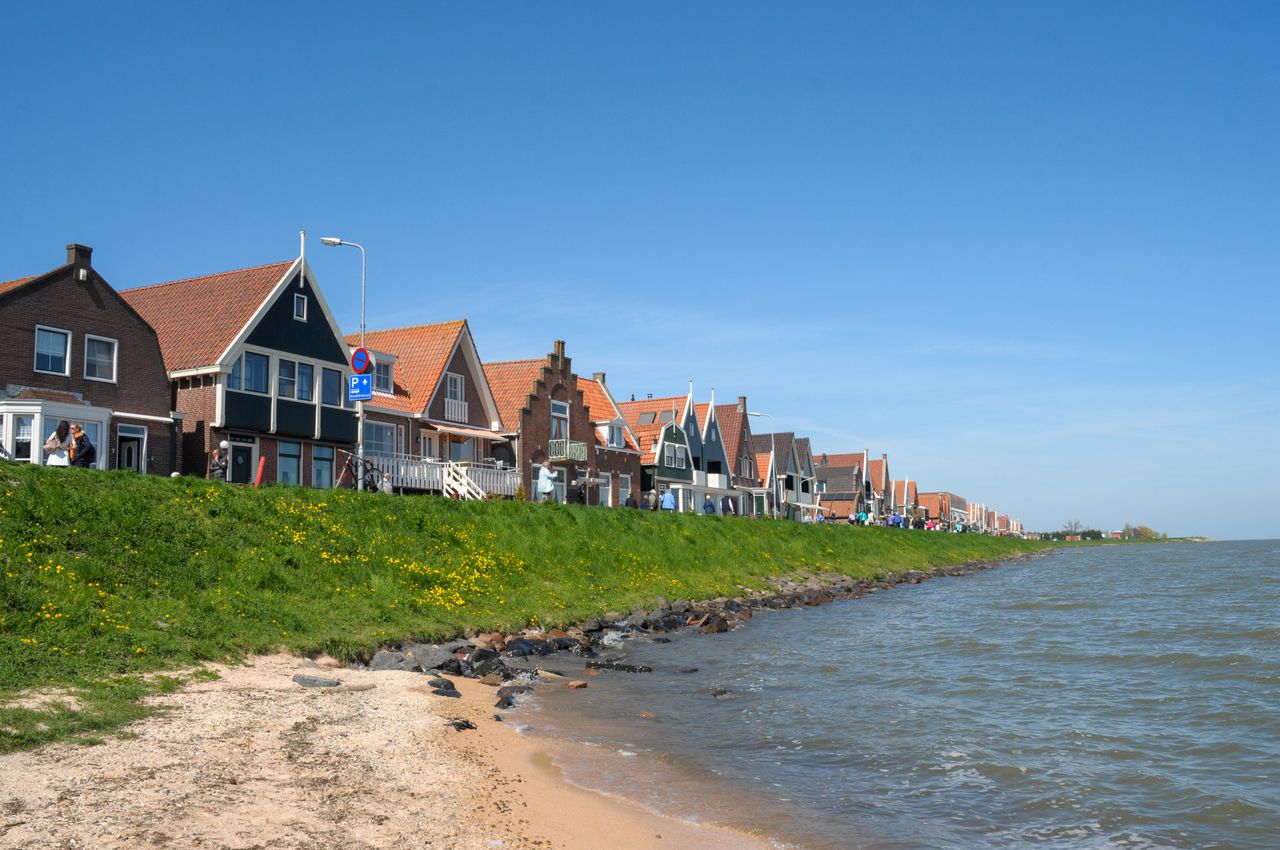 Hilera de casas tradicionales de Volendam junto al agua, reflejadas en un canal en un día tranquilo.