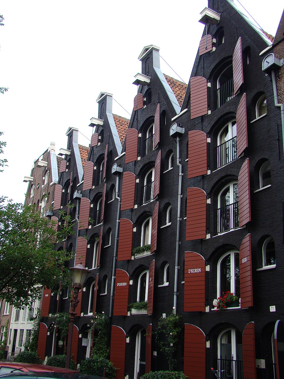 Edificio histórico de ladrillo negro con puertas rojas en Prinseneiland, uno de los barrios más tranquilos de Ámsterdam.