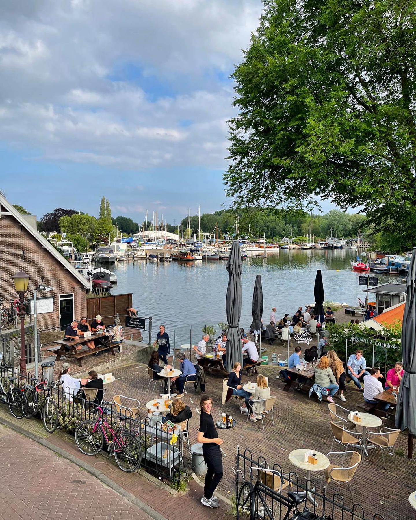 Terraza de Café ’t Sluisje en Nieuwendam, con clientes disfrutando junto al agua en un ambiente tranquilo y local.