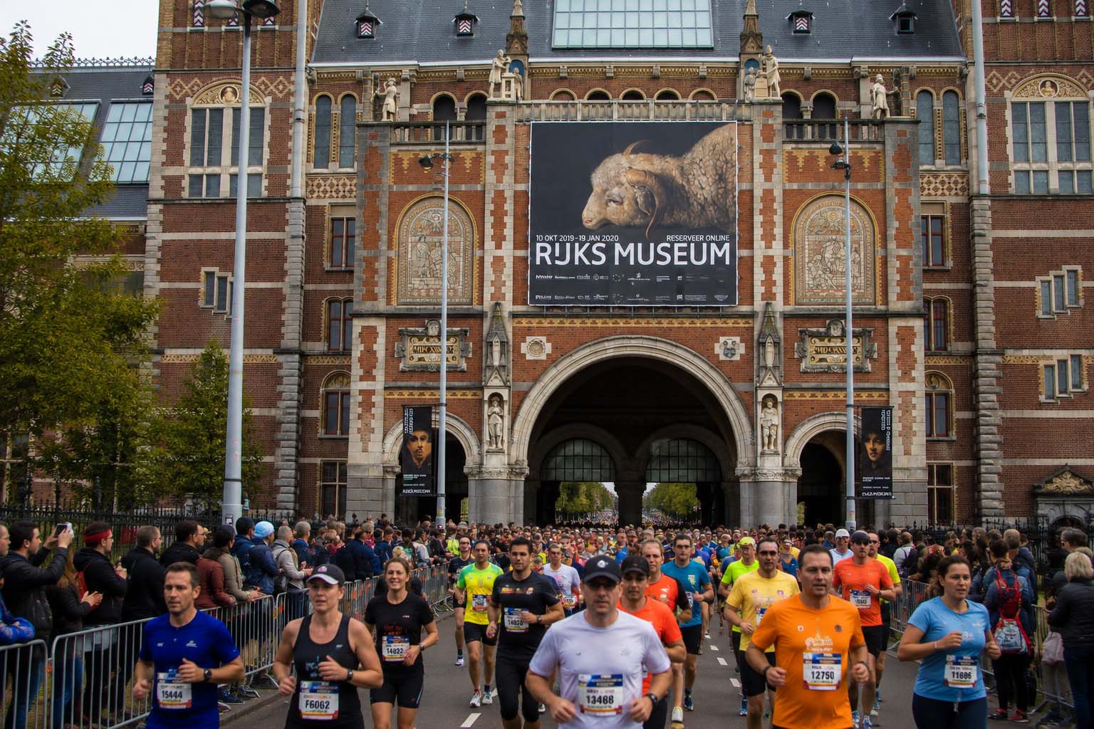 Recreación de corredores del Amsterdam Marathon pasando bajo el Rijksmuseum durante la carrera, uno de los puntos más emblemáticos del recorrido.