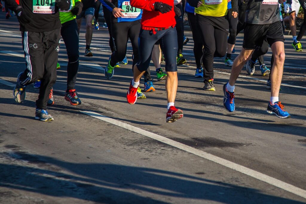 Grupo de corredores amateur durante una carrera, con un primer plano de sus piernas mientras avanzan juntos.
